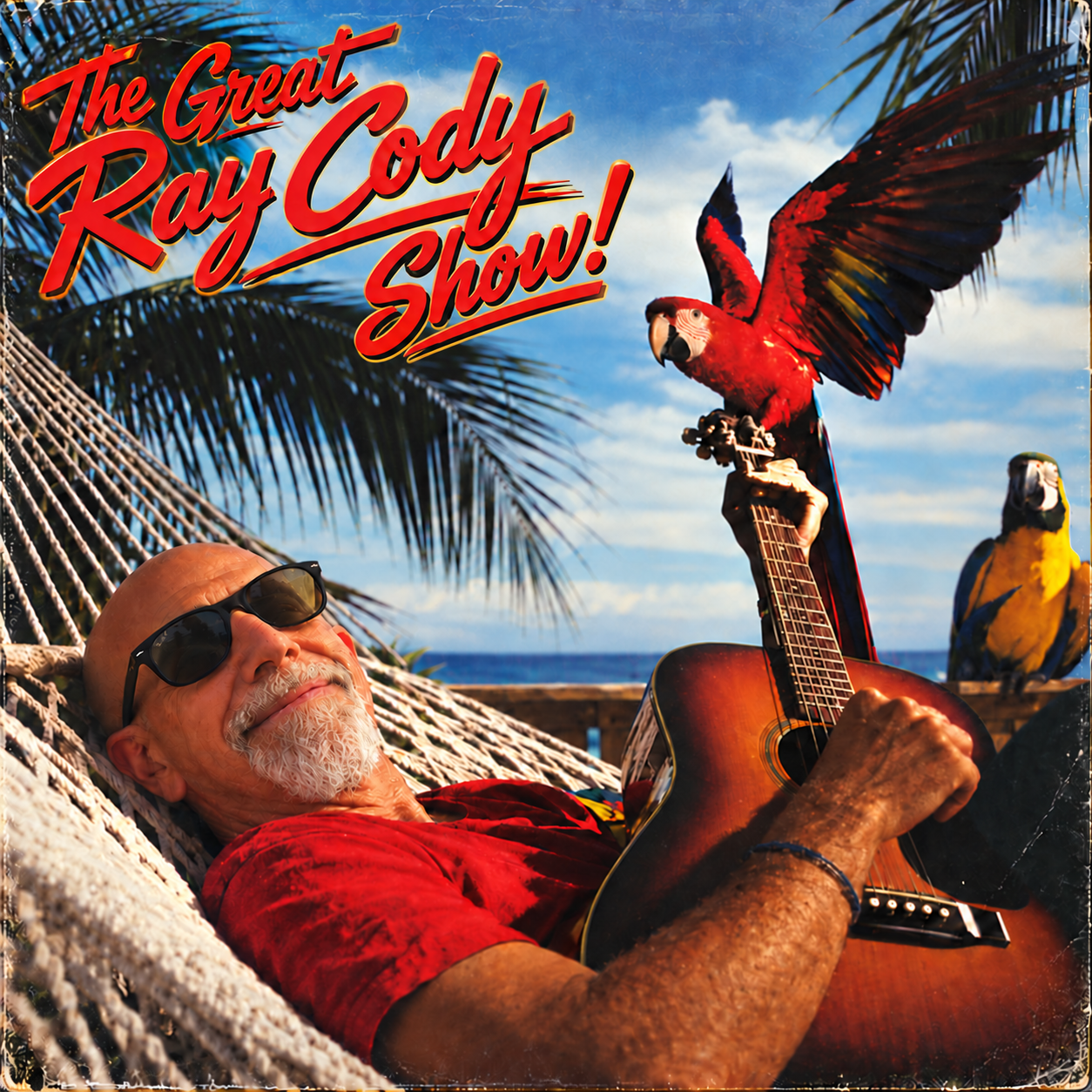 The Great Ray Cody reclining in a beach hammock with an acoustic guitar beneath palm trees and two parrots